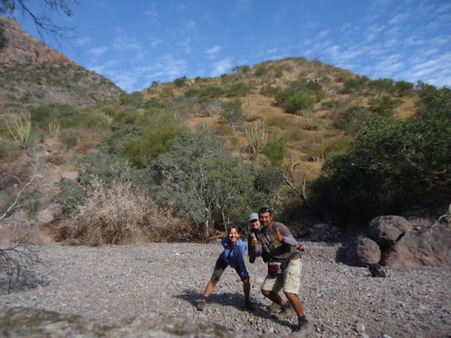 Two guides and guests laughing together on a sunny desert trail near Loreto