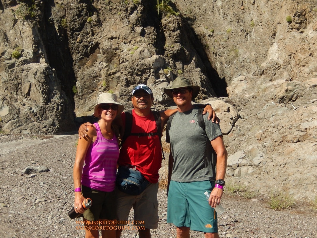 Four hikers posing and laughing inside a smooth-walled slot canyon near Loreto