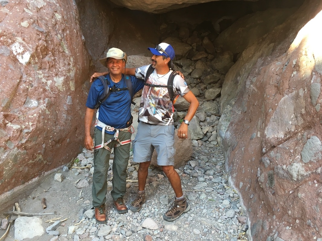 Two guides smiling together inside a narrow canyon cave passage near Loreto