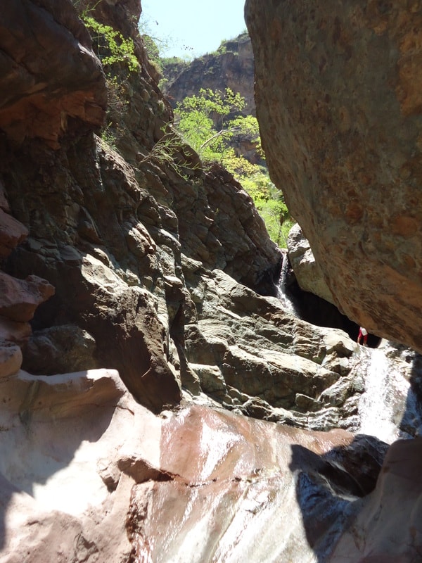 Hiker beside a waterfall cascading into a natural pool in the Sierra de la Giganta