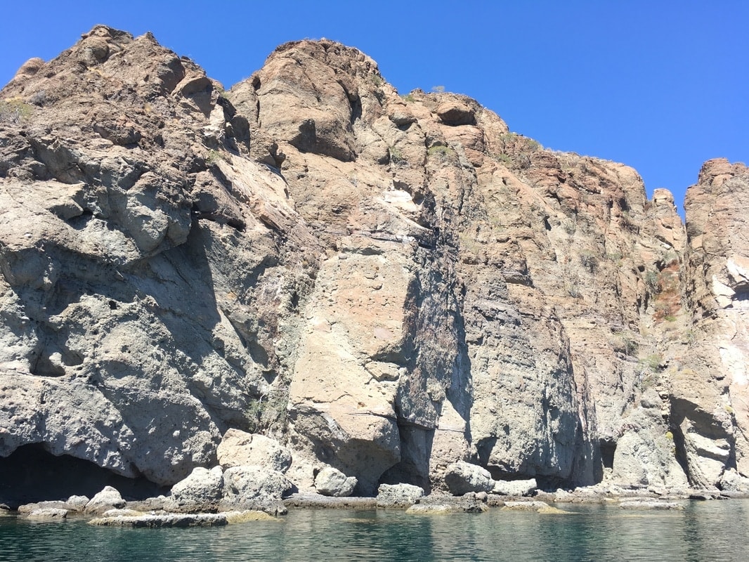 Towering volcanic rock cliff face with sea caves rising from the Gulf of California near Loreto