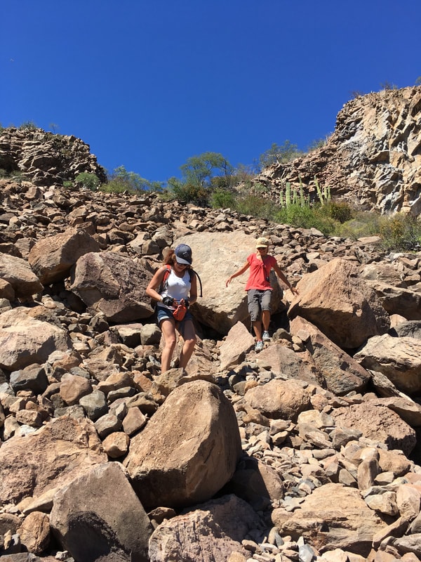 Hikers scrambling over giant boulders on the trail to Mission San Javier